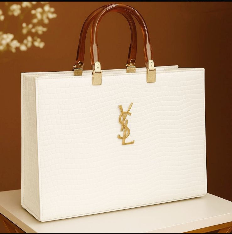 White handbag with brown handles on a white surface against a brown background